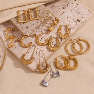 Collection of gold and silver geometric earrings on travertine stone and silk fabric