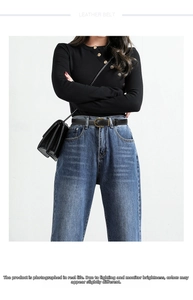 Close-up of a black leather belt with a vintage textured gold buckle on denim jeans