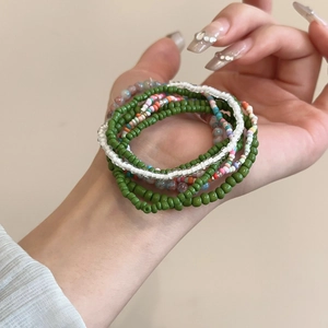 Detail of colorful Bohemian seed bead bracelets showing multi-layered texture and green tones