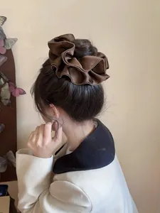Detailed view of an elegant coffee silk satin scrunchie on a low bun hairstyle