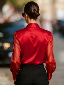 Detail of red silk shirt featuring semi-sheer striped sleeves and elegant back tailoring