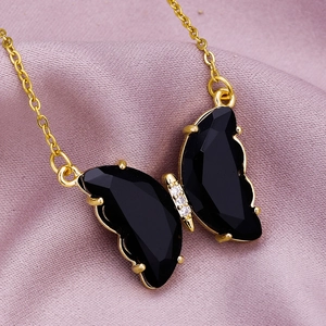 Macro shot of gold butterfly pendant with faceted black crystals and clear stones