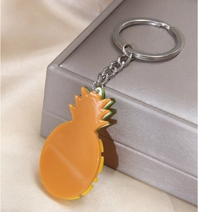 Vue détaillée d'un porte-clés ananas élégant sur soie champagne avec boîte cadeau