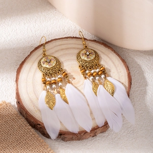 Detail of bohemian feather earrings with wood beads on natural wood background