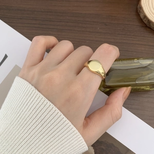 Macro detail of minimalist gold oval ring on model hand with elegant vintage aesthetic