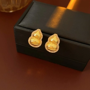 Detailed close-up of gold gourd earrings with sparkling zircons on a luxury jewelry box