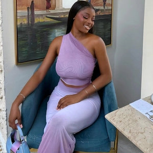 Detail of purple one-shoulder mesh top and trousers set on a velvet chair
