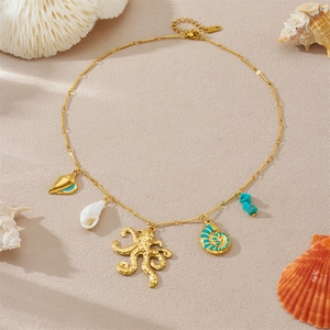 Gold bamboo chain necklace with blue octopus and shell charms on sandy beach background