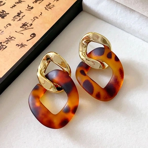 Detail shot of acrylic amber hoops with gold textured metal links on a white gift box