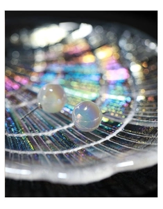 Macro shot of iridescent sphere stud earrings with a dreamy rainbow pearlescent finish