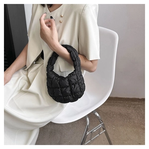 Detail shot of black quilted puffer bag with high-gloss finish on a model