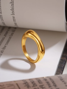 Macro detail of glossy gold-plated irregular geometric ring on white book pages