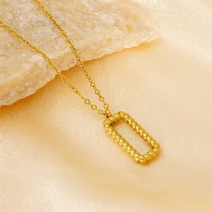18k gold plated hollow rectangular bar pendant necklace on a textured stone and silk background