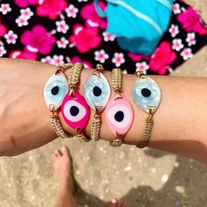 Detail of five-piece Evil Eye braided bracelets set in pink and white beach style