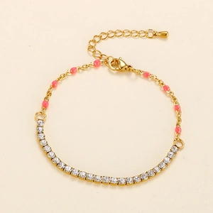 Detail of golden bracelet with white rhinestones, pink beads and heart charm