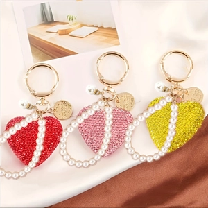Dettaglio di portachiavi a cuore con strass e perle nei colori rosso, rosa e giallo brillante