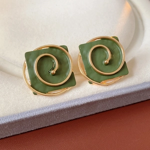 Detailed view of vintage green square earrings with golden spiral pattern in a gift box