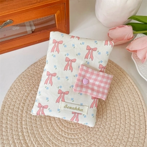 Detail of fabric book cover with pink bows and heart button on a straw mat background