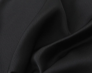 Detail shot of the glossy black satin fabric showing smooth texture and drape of the top