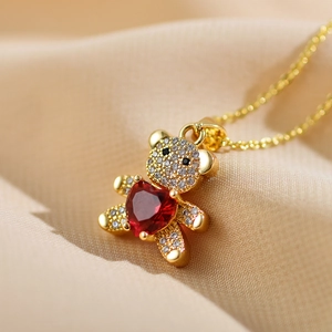 Macro shot of gold bear pendant with red heart gemstone and white zircon pavé details