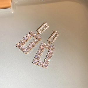 Detailed macro shot of gold square hollow earrings featuring shimmering white zircon stones