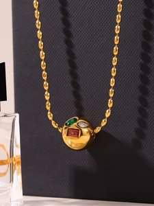 Détail du pendentif sphère dorée avec pierres colorées et chaîne à billes olive