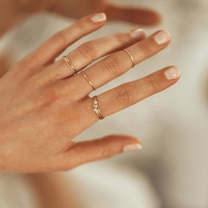 Stackable gold minimalist ring set with December birthstones on female hand