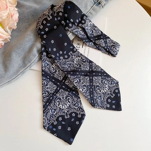 Detail of navy blue paisley silk scarf with intricate floral pattern on white background
