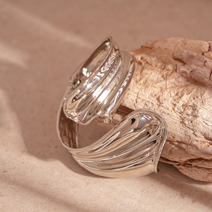 Macro view of polished silver fluid organic leaf ring on a natural wooden display