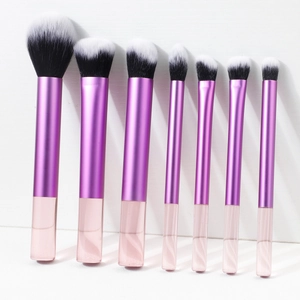 Dettaglio di 7 pennelli da trucco professionali con manici rosa trasparenti e ghiere viola