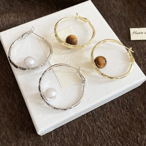 Close-up of hammered gold and silver hoops with pearl and tiger eye stone beads
