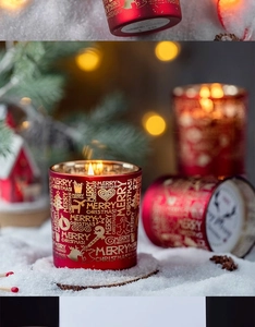 Detail einer roten Weihnachtskerze mit goldenen Rentier-Motiven in verschneiter Umgebung