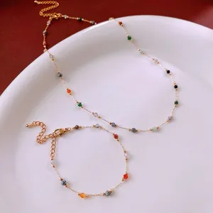 Minimalist gold chain jewelry set with colorful faceted beads on a ceramic plate