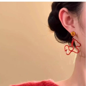 Detail of red hollow heart earrings with gold Fu character stud on a female model