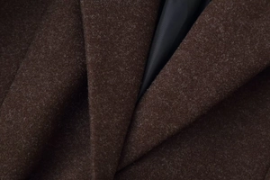 Detailed close-up of dark brown wool coat lapel with premium fiber texture and black lining