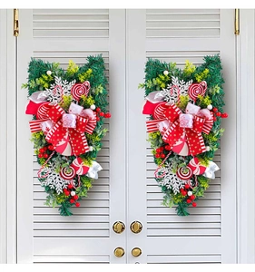 Close-up of red and green Christmas candy door swags with bows on a white shutter door
