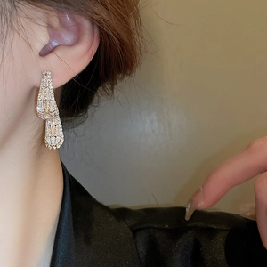 Macro detail of long gold drop earrings with sparkling zircon fringe on a model's ear