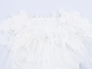 Detail of white knitted bodysuit with intricate lace trim and a size S tag