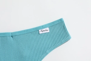 Close-up of ribbed teal cotton fabric texture with white Napaluo brand woven label