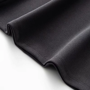Detailed close-up of premium black crepe fabric texture and fine hem stitching on the dress