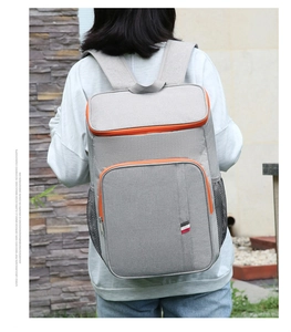 Gros plan sur un sac à dos isotherme gris avec des zips orange et des bretelles larges