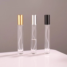 Three 10ml glass spray bottles with gold silver and black aluminum caps on reflective surface
