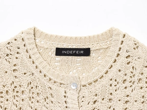 Detail shot of Indefeir openwork knit sweater with pearl button and brand label