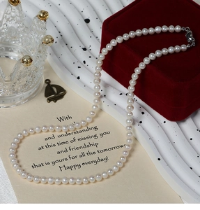 Detailed view of 5-6mm white freshwater pearl necklace with silver lobster clasp on velvet
