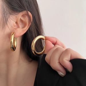 Macro shot of minimalist thick gold hoop earrings with a high-polished metallic finish