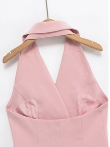 Détail d'un haut dos nu rose avec décolleté en V sur un cintre en bois sur fond blanc