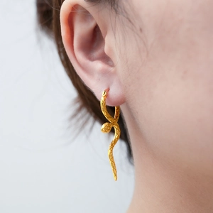 Boucles d'oreilles serpent dorées vintage avec texture à écailles portées par un modèle