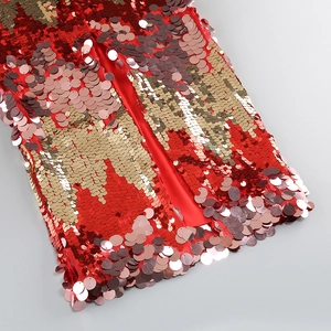 Detailed macro view of vibrant red and champagne gold sequins on an evening dress