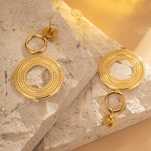 Detail of layered gold earrings with grainy texture on stone display background