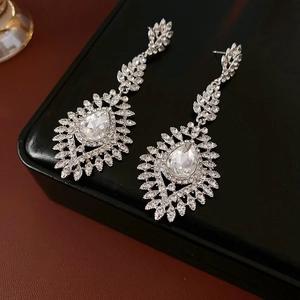 Detail view of silver drop earrings with wheat-shaped rhinestones on black leather box